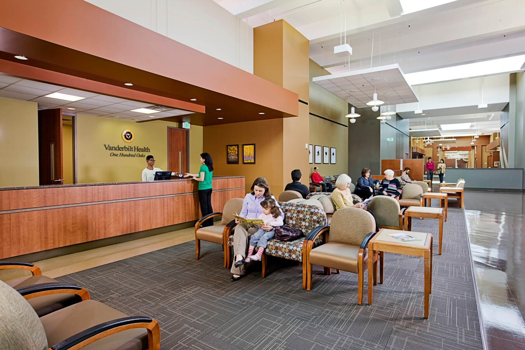 woman and girl sit in waiting room near reception desk