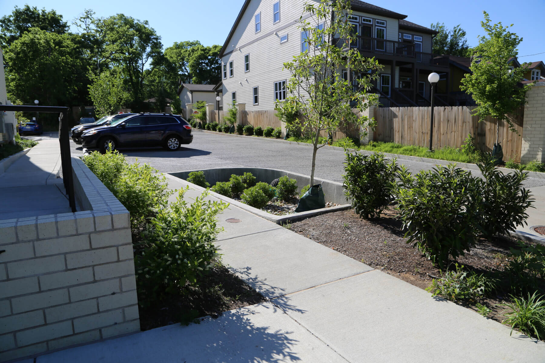 A sidewalk with plants and trees next to The Waverly