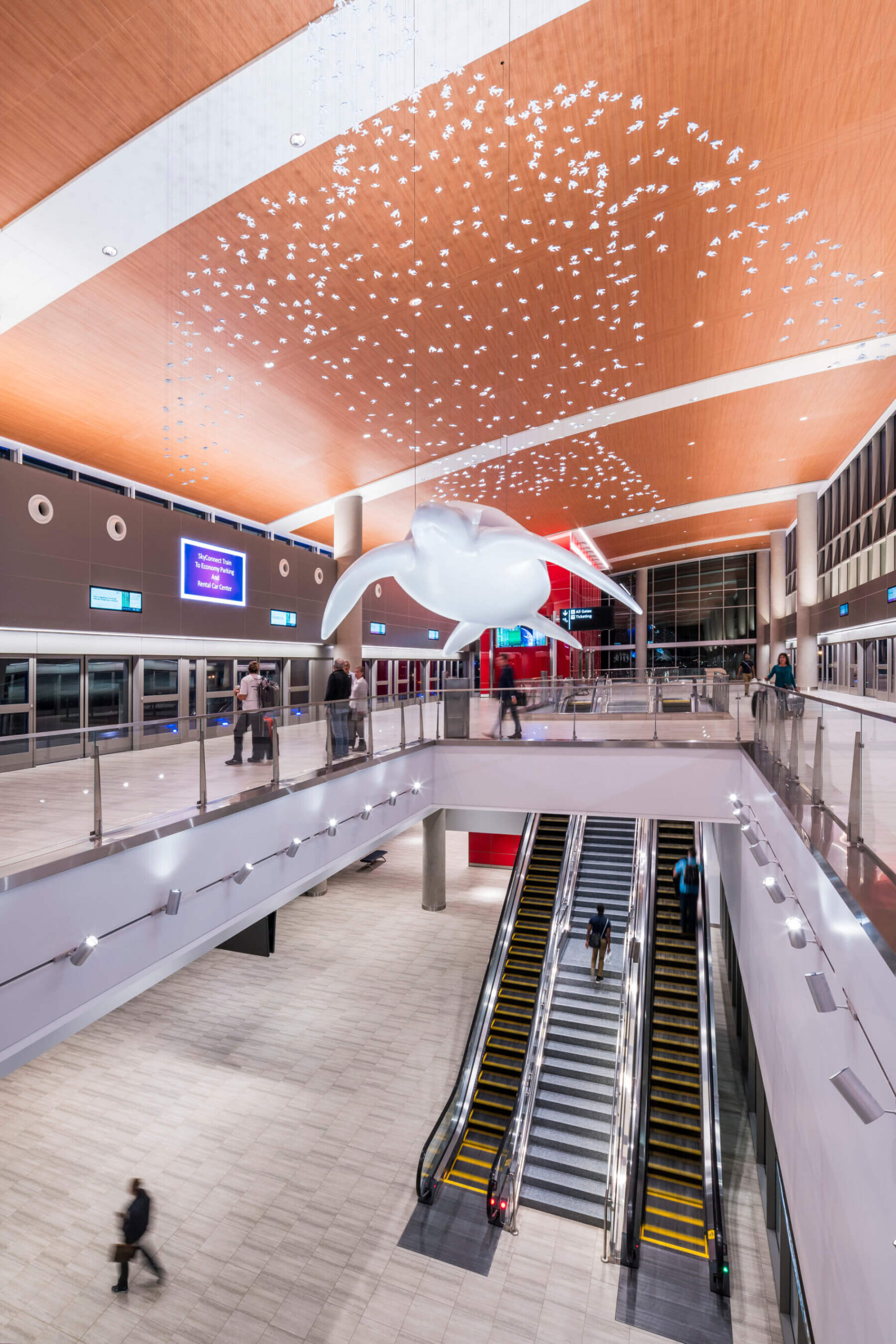 a large turtle art installation suspended from the ceiling at Tampa International Airport at dusk