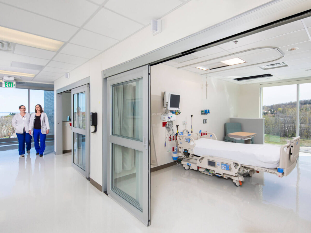 medical providers walk to an unoccupied patient room