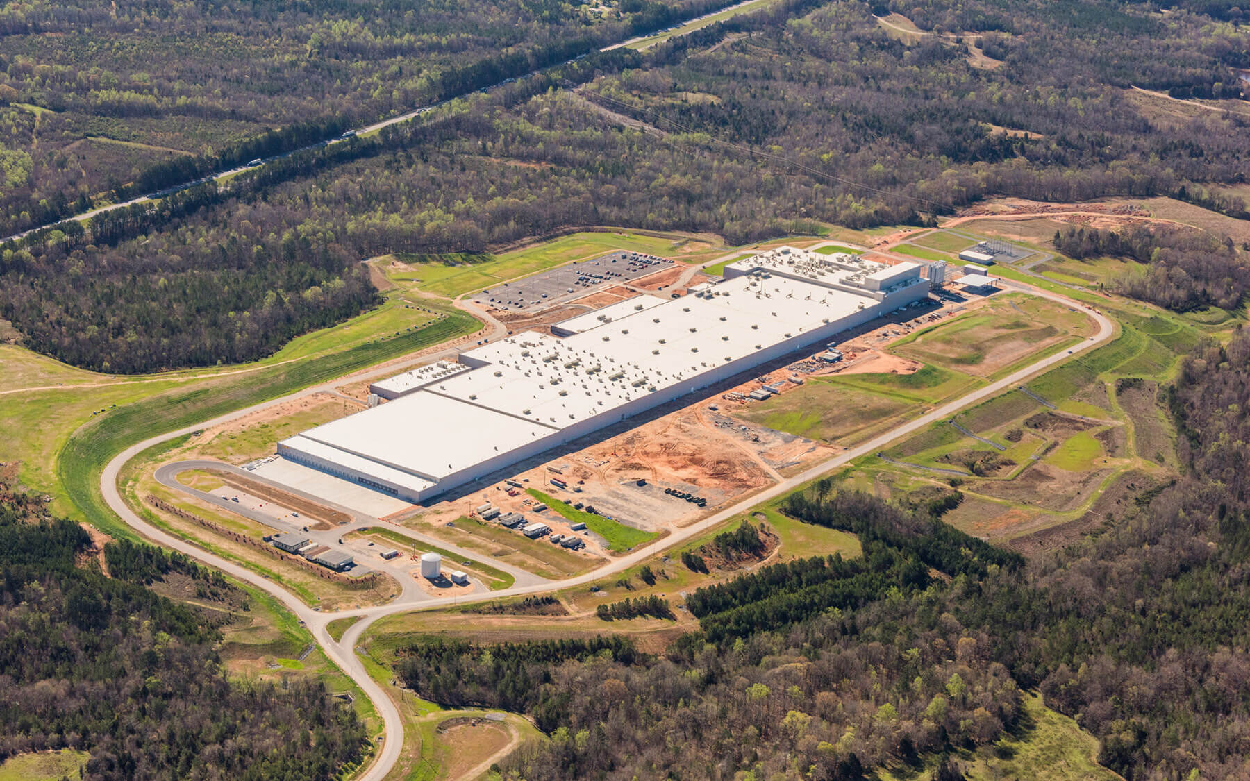 birds-eye-view of the unfinished plant with surrounding acreage of trees and roads