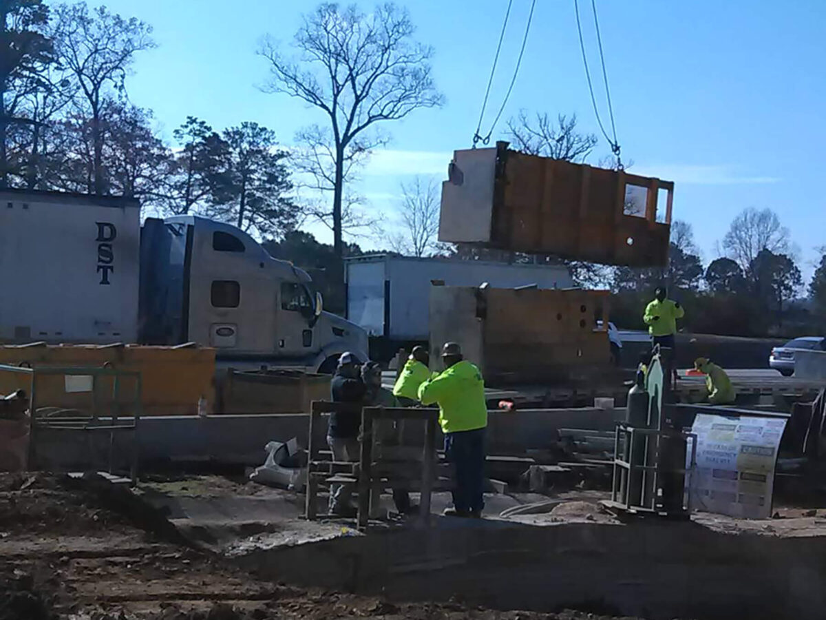 Workers assist a crane on a construction site.