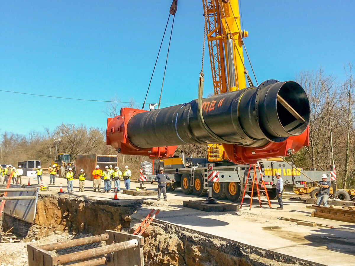 A large pipe being lowered into the ground by a crane