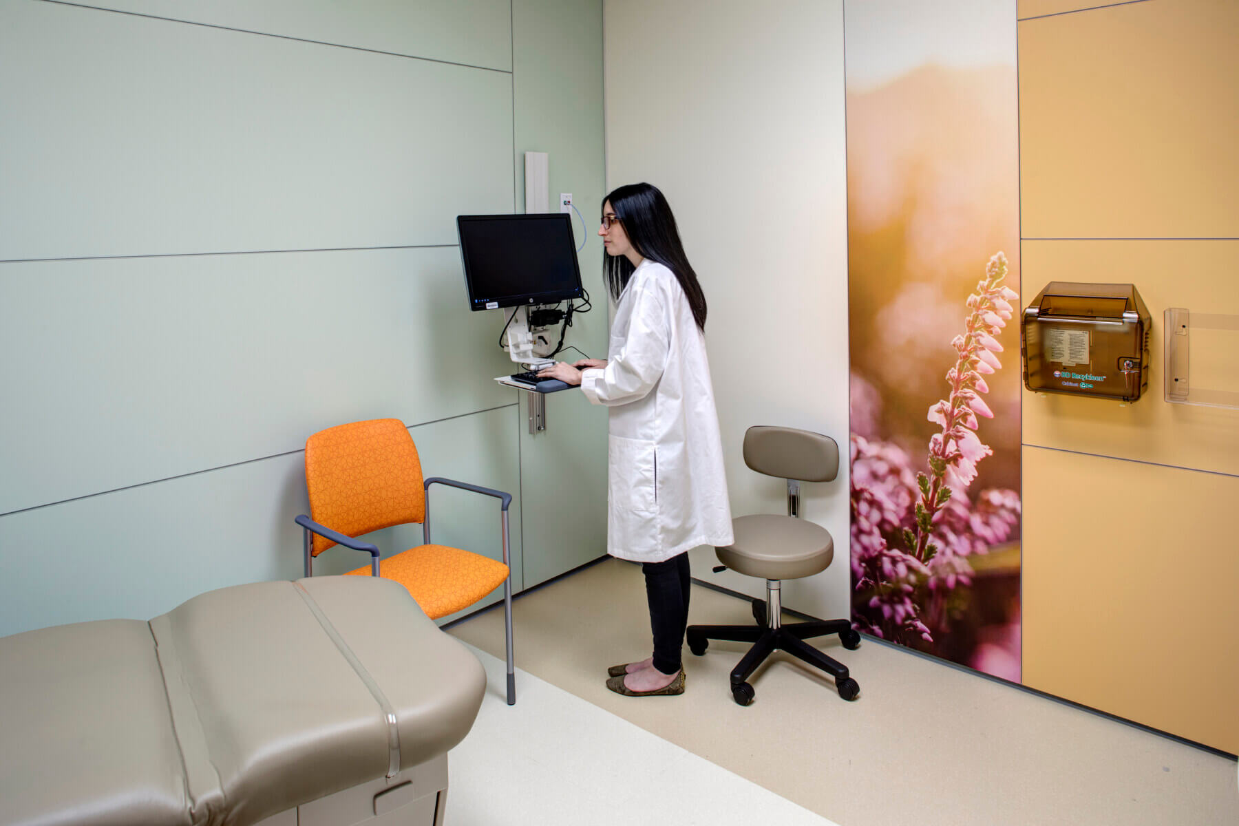 a doctor standing at the computer in an exam room