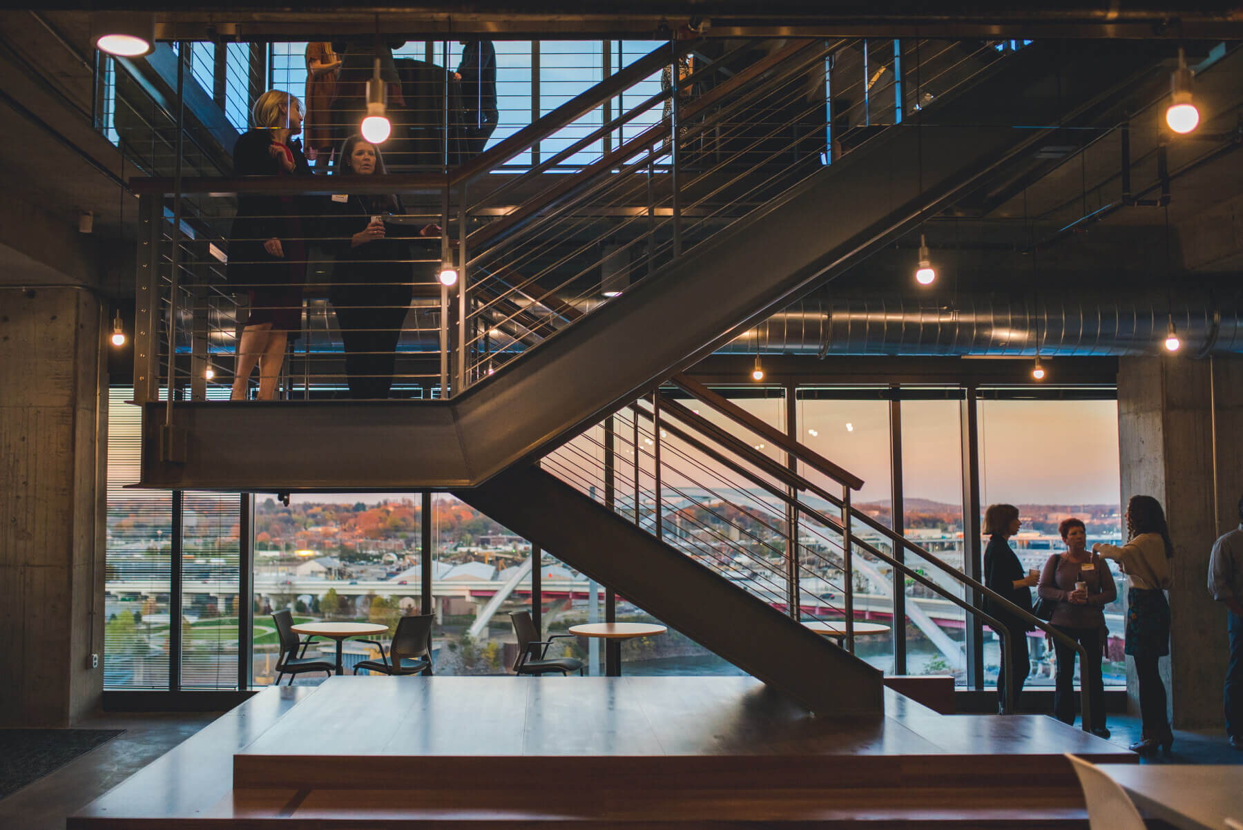 view of open people talking near the staircase during an event overlooking outside sunset
