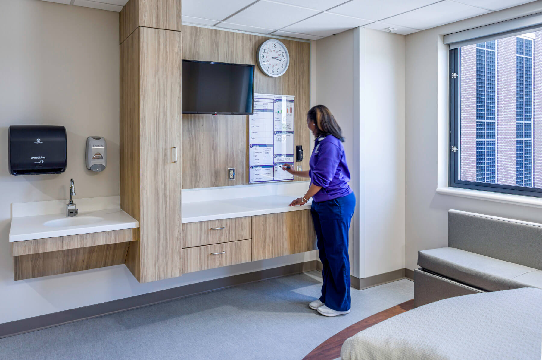 nurse writing on a white board in a patient room