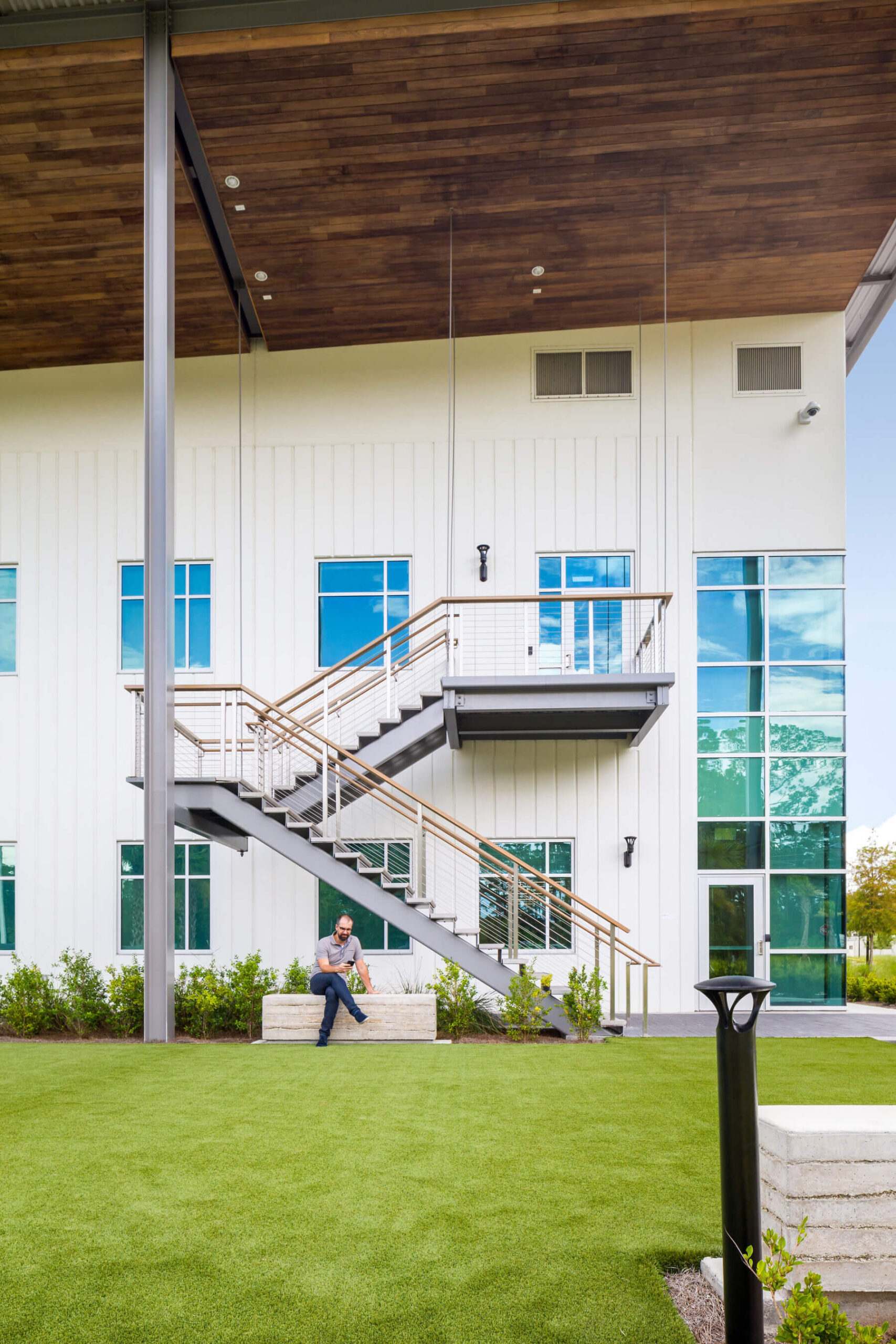 man sits in the park area with exterior staircase in the background