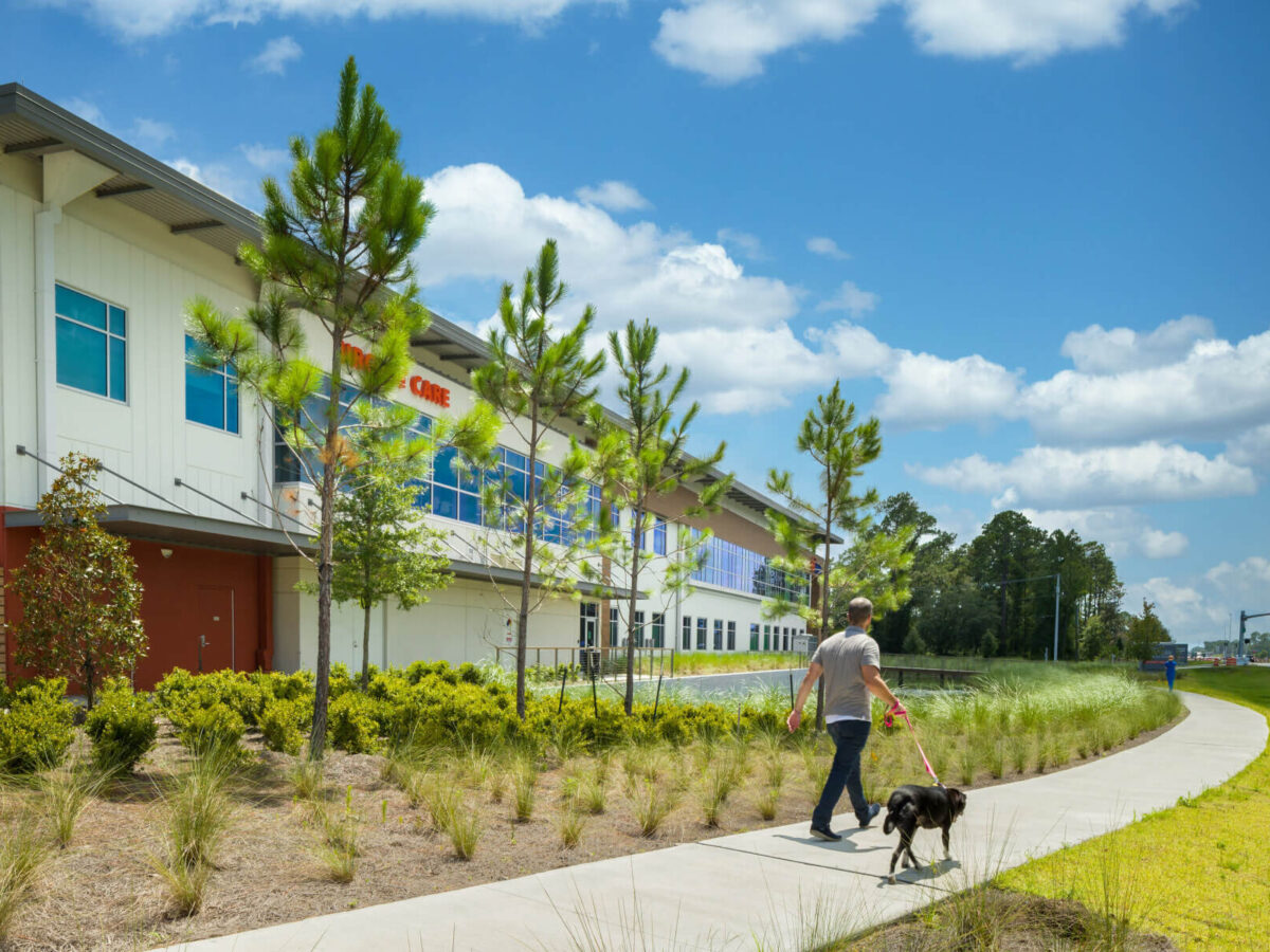 man walks dog along a path outside