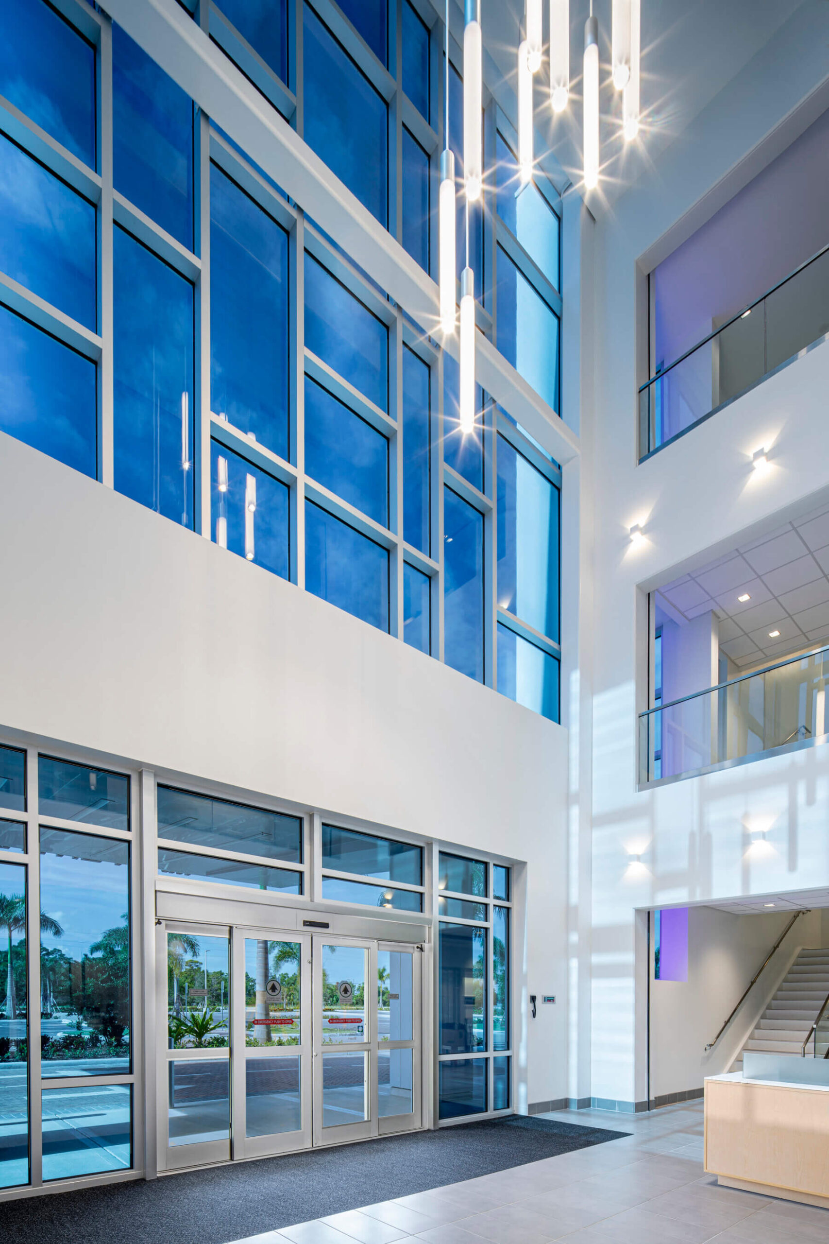 a two-story lobby with large glass windows and a pendant light fixture