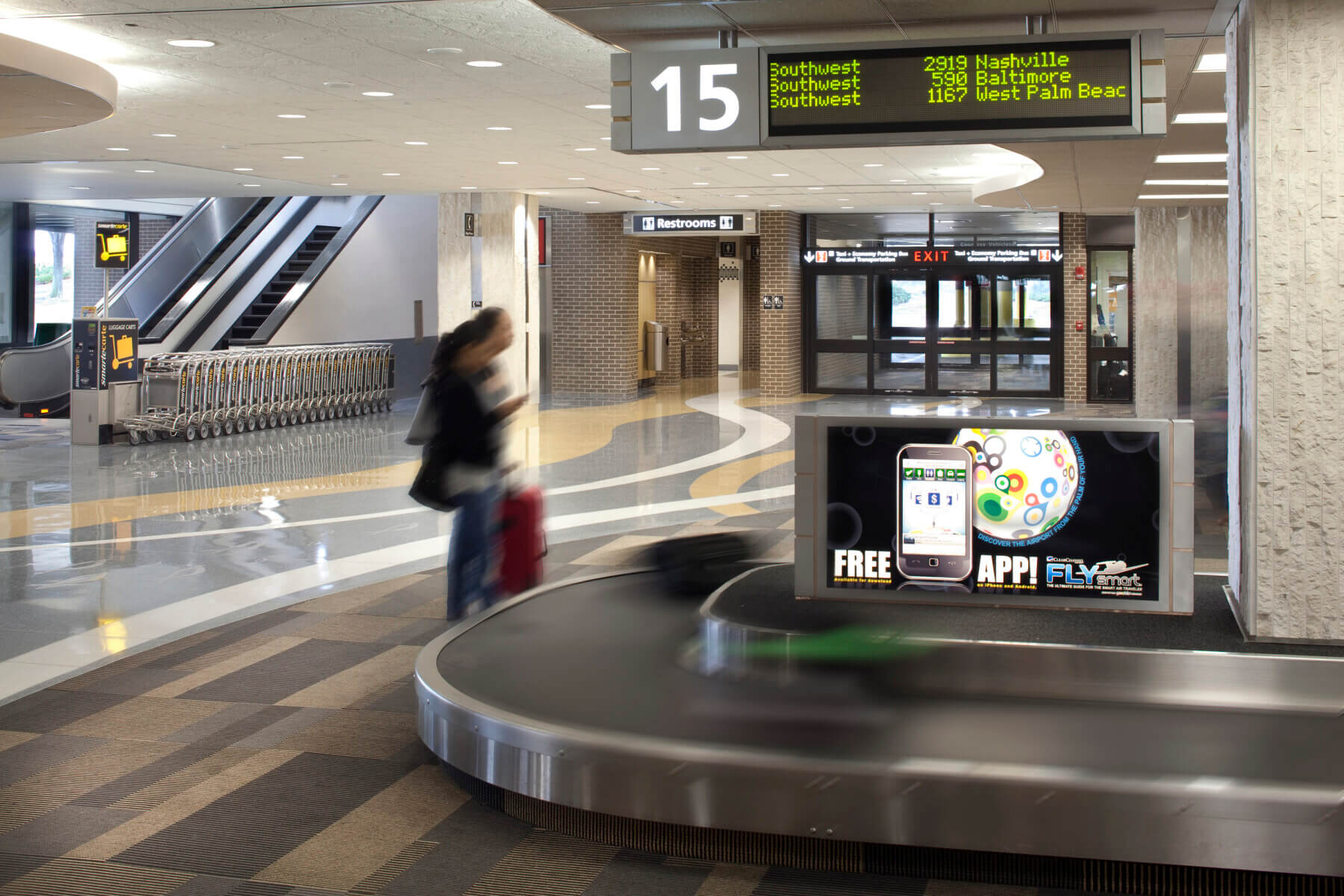 a woman standing at a carousel in the baggage claim area at Tampa International Airport