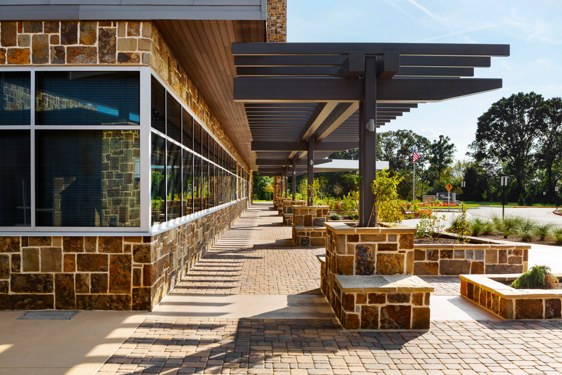 outdoor walkway with stone benches and shade from pergolas