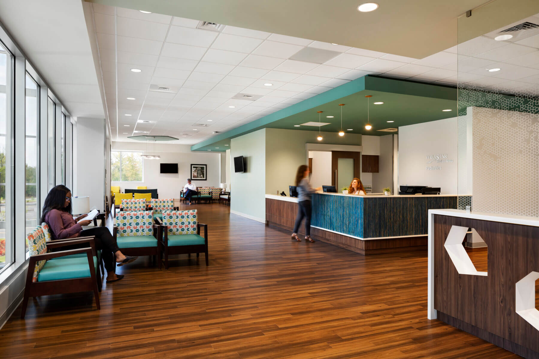 patients check in at the reception desk while others wait in the seating area