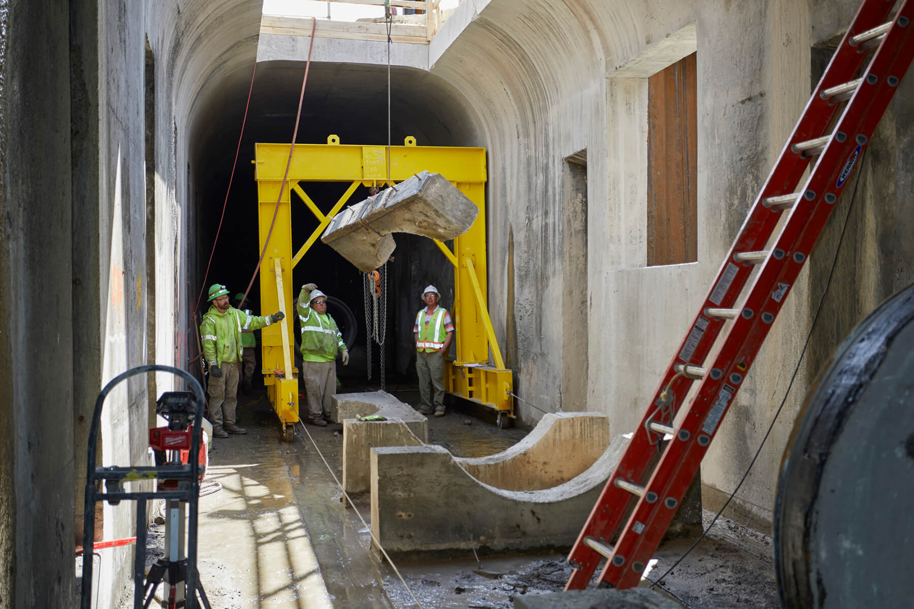 Workers seen along the underground concrete pipe route with ladder in foreground.