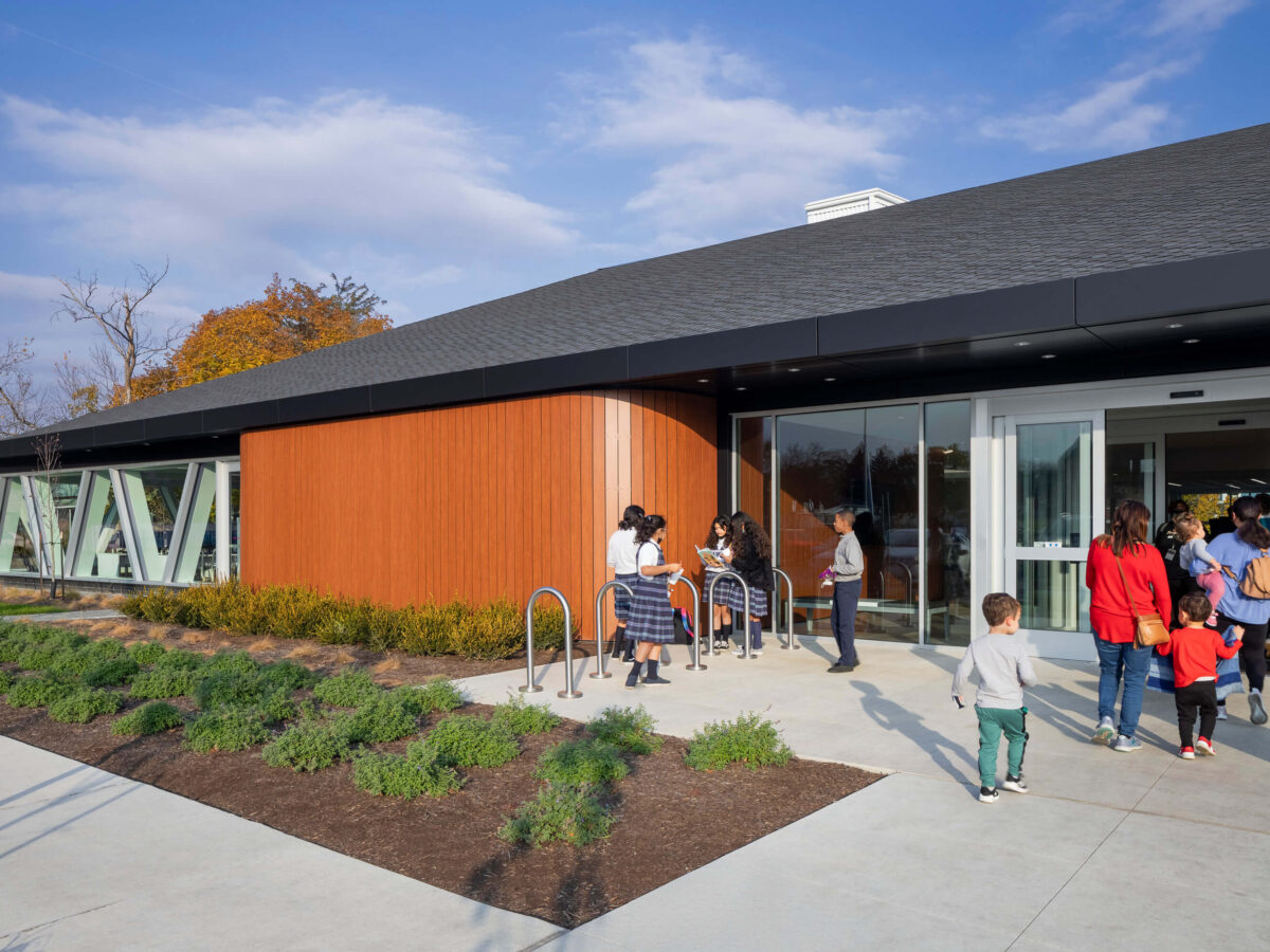 exterior entrance of the library with school children in uniforms walking in