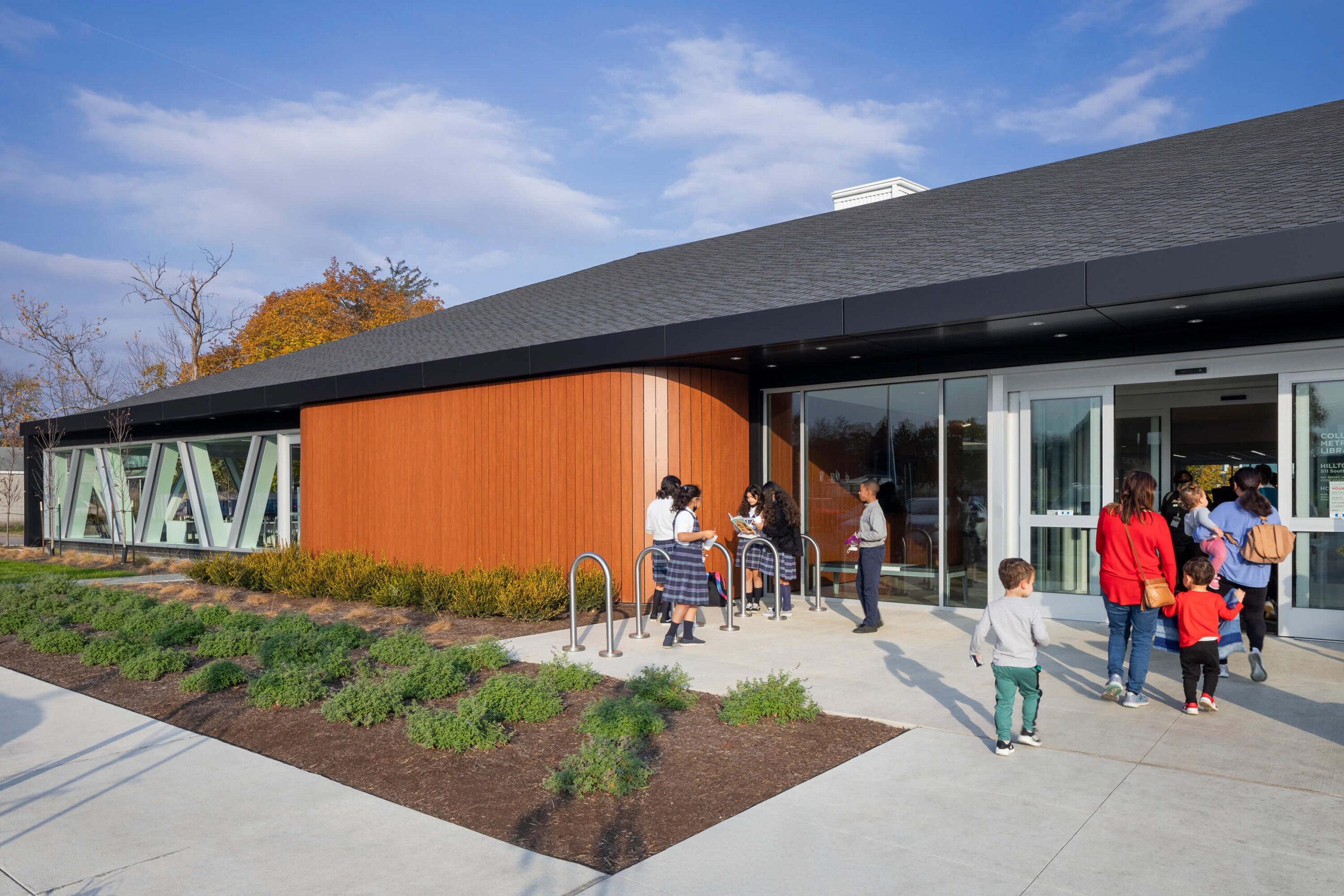exterior entrance of the library with school children in uniforms walking in