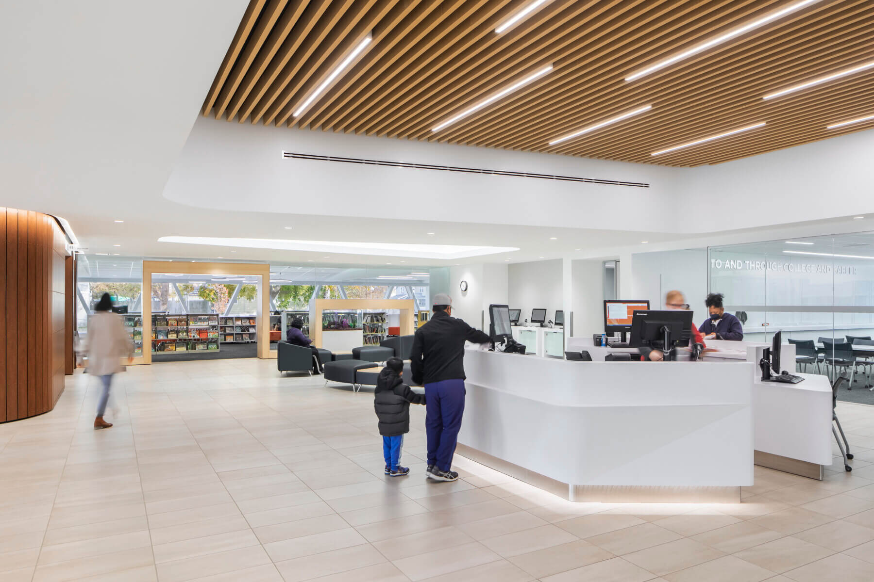 a man and boy approach the front reception desk of the library