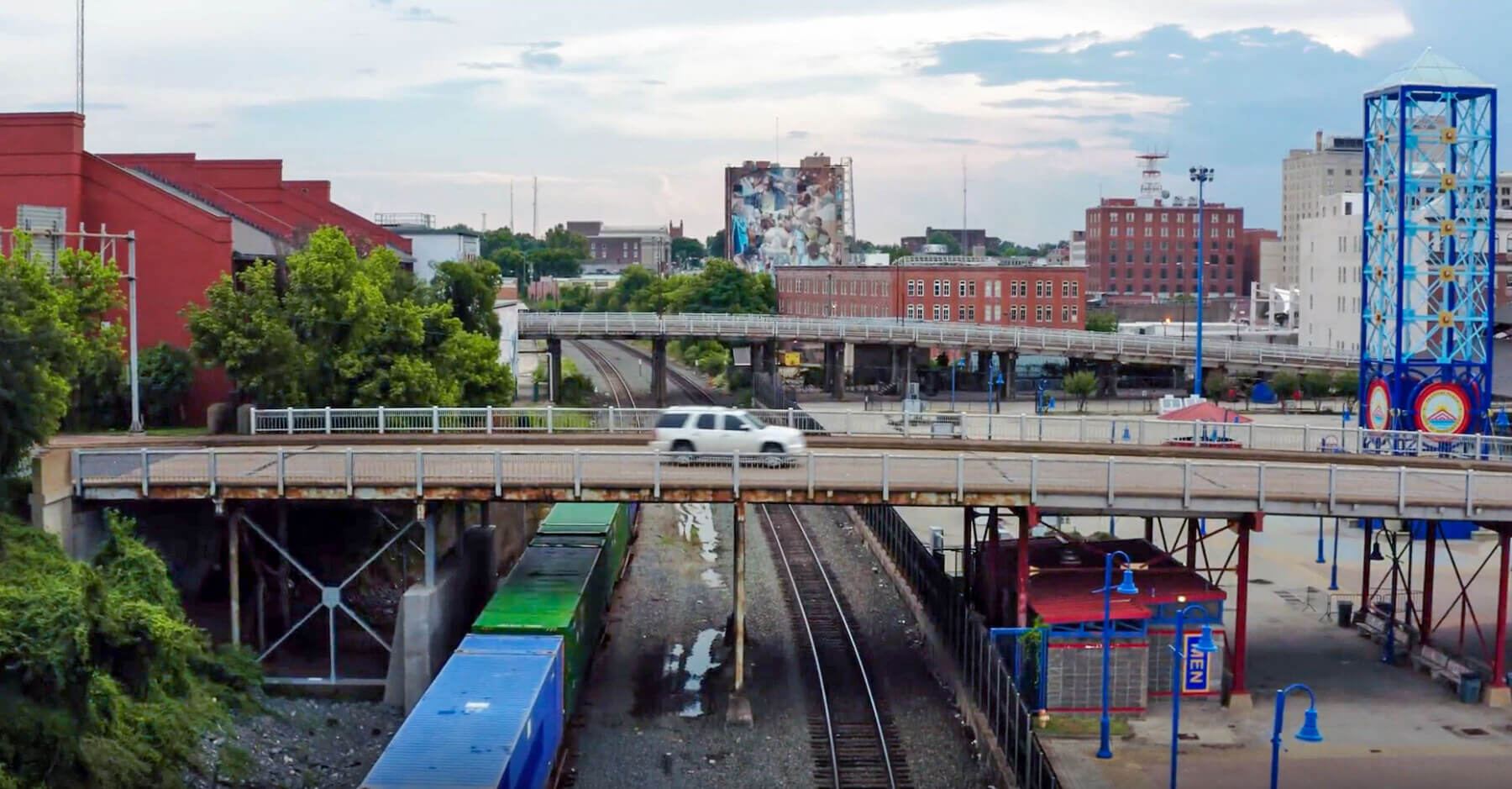 a bridge over railroad tracks with a car driving