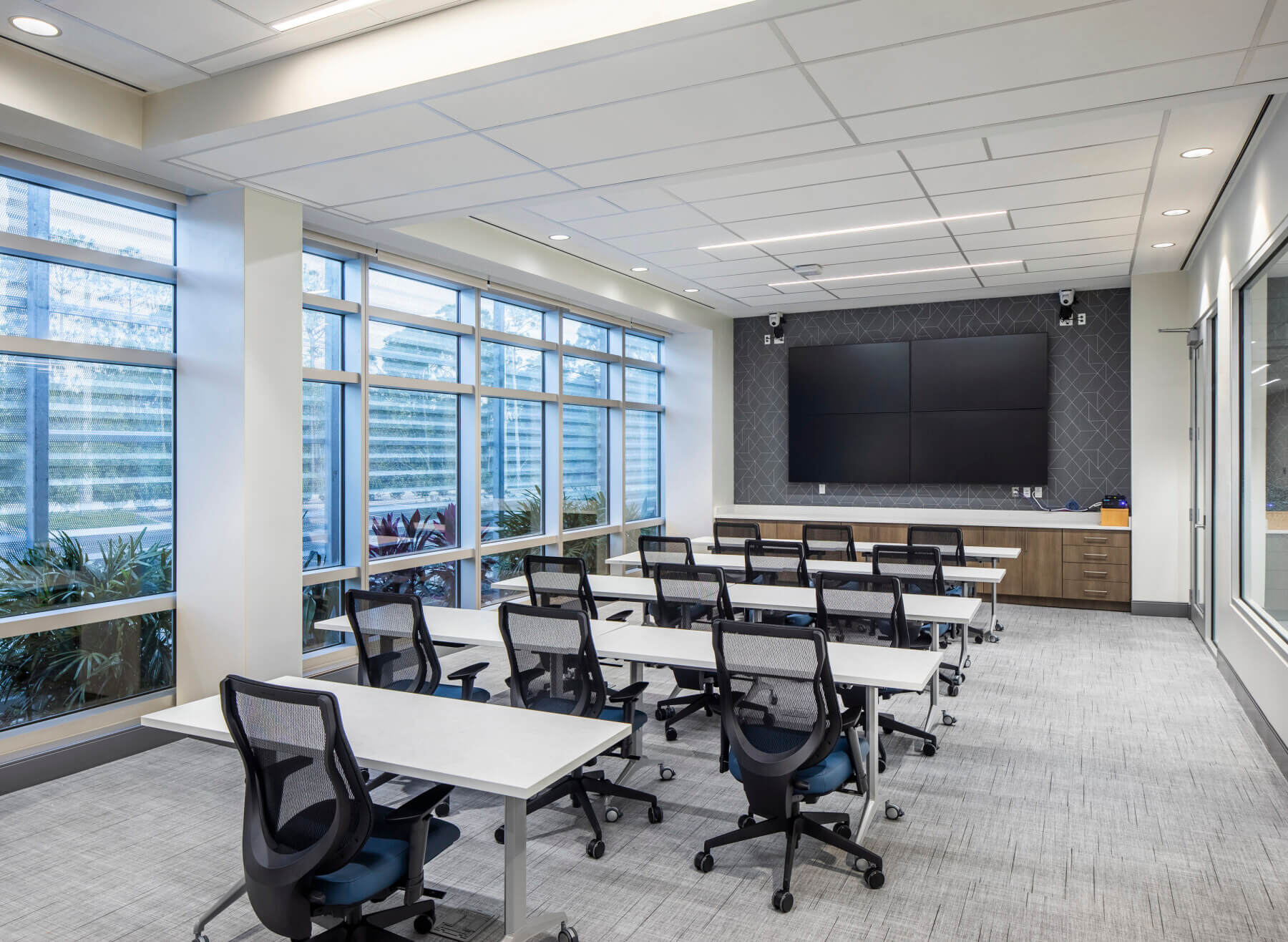 classroom with tables and desk chairs and a large monitor on the wall