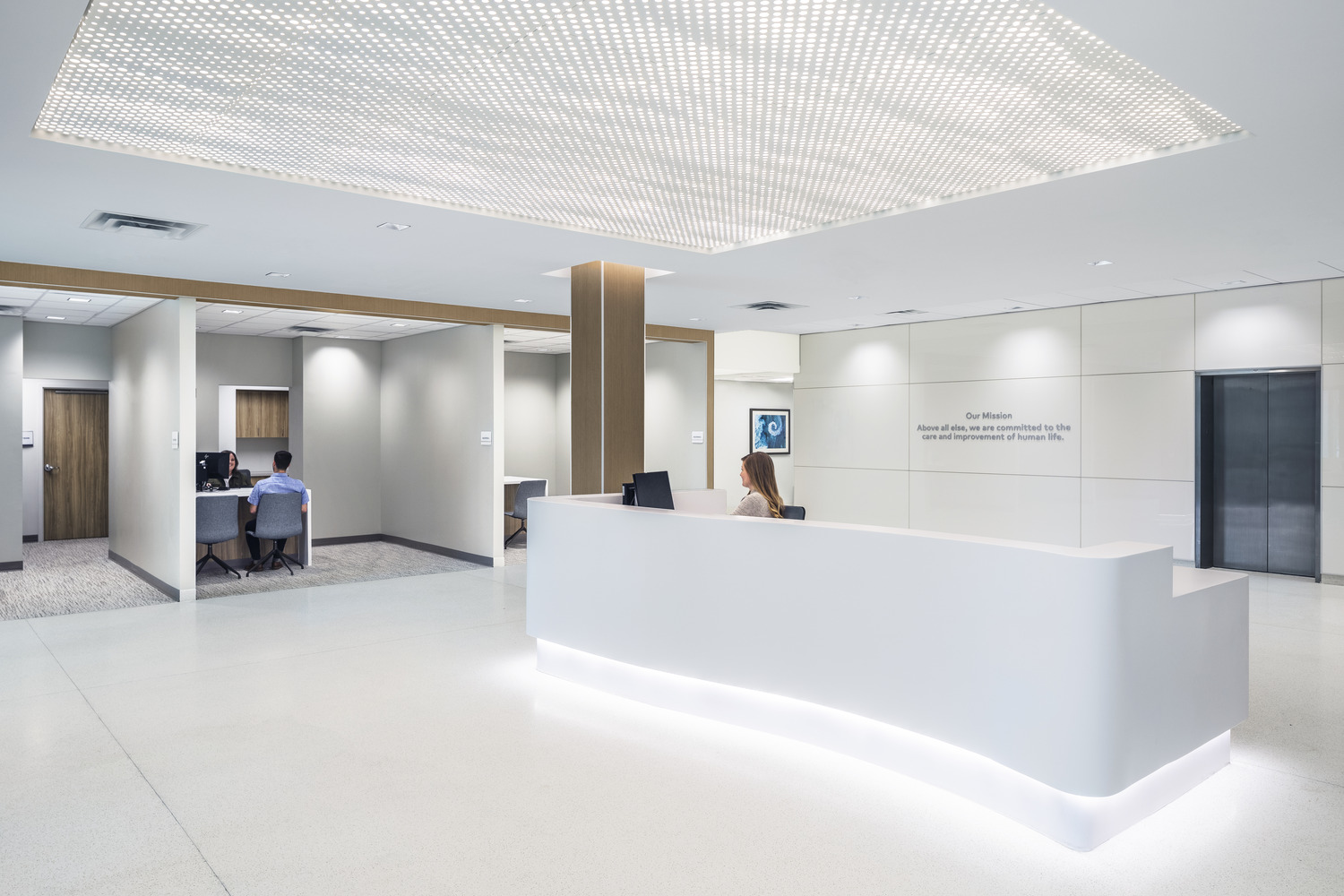 A person sitting at a reception desk and a person sitting at a registration desk