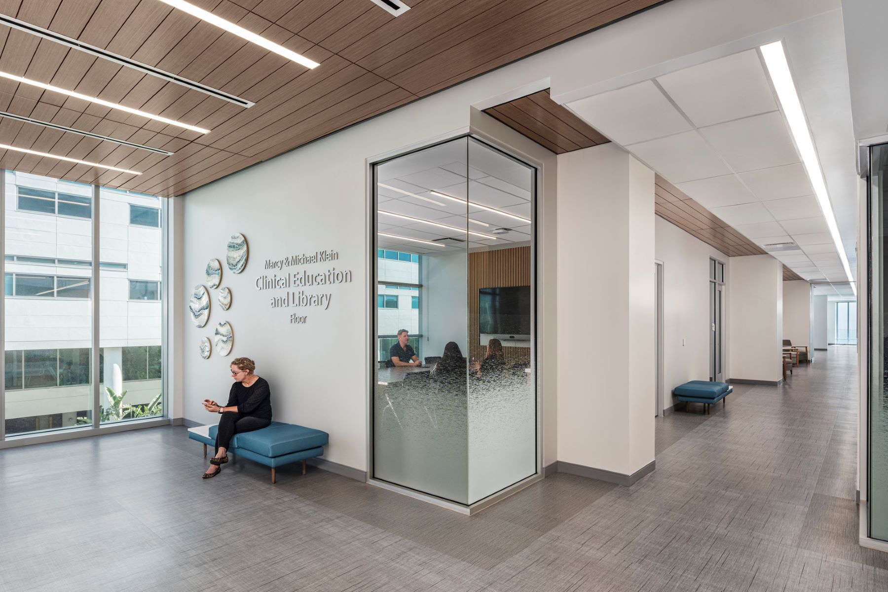a person sitting on a bench outside of a medical library room
