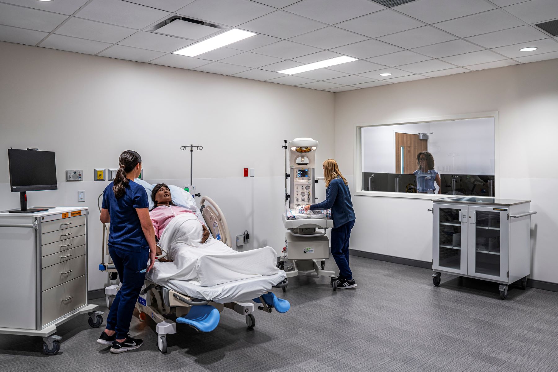 two medical students attending to a simulation patient in a hospital bed