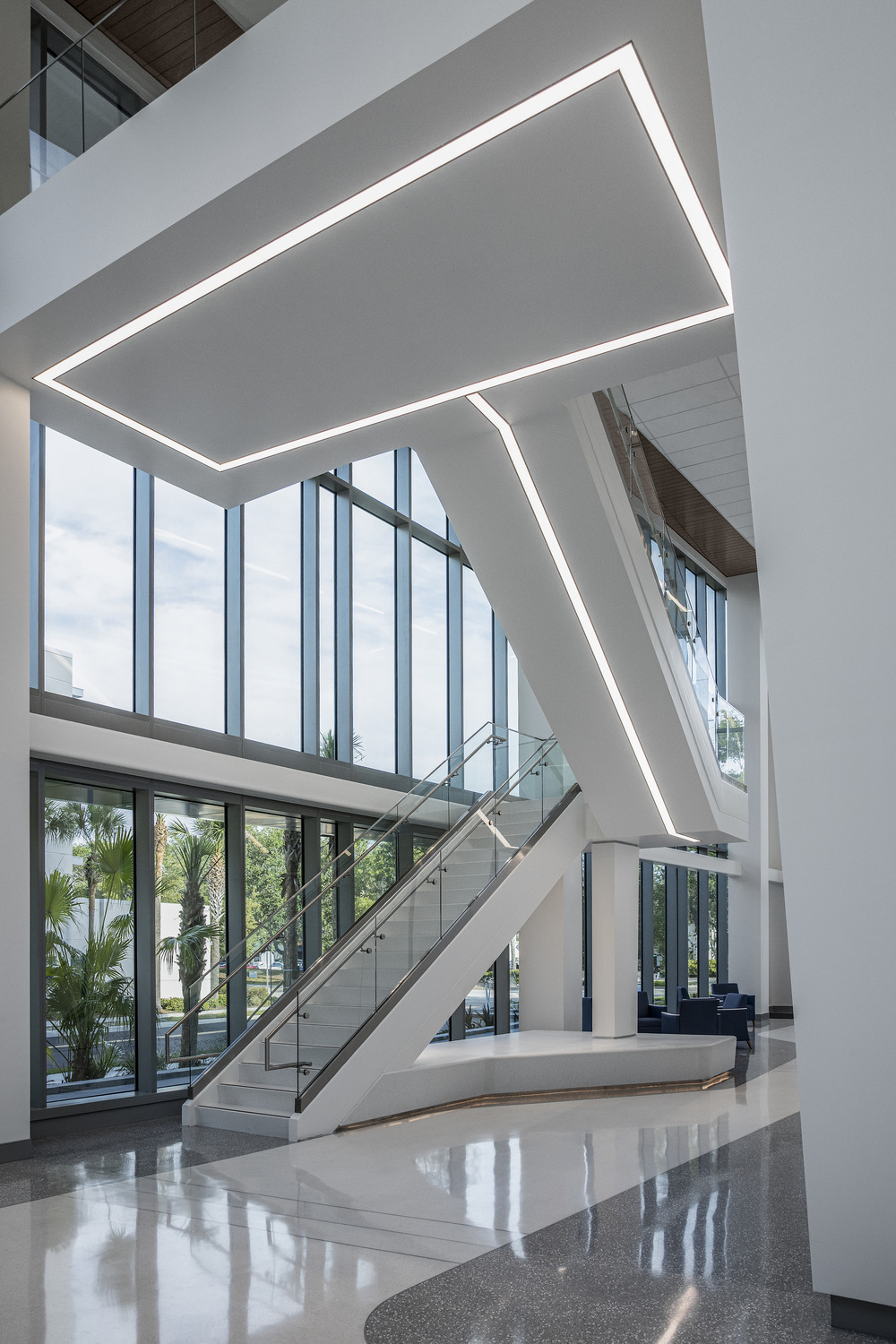 a white staircase in front of a two story glass wall