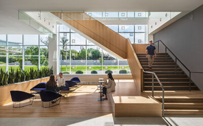 people sitting in chairs and climbing the staircase in an office building