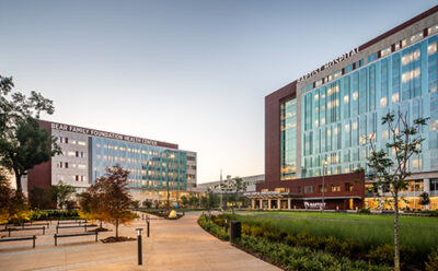 a sidewalk in front of a hospital and medical office building with glass windows