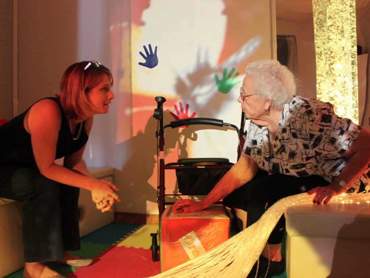 two women talk in a dark room with colored lights