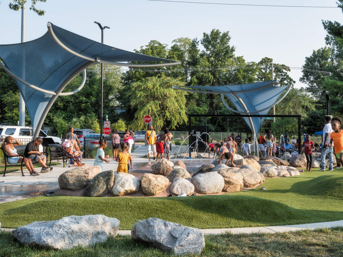 Children playing at a park with rocks and fountains