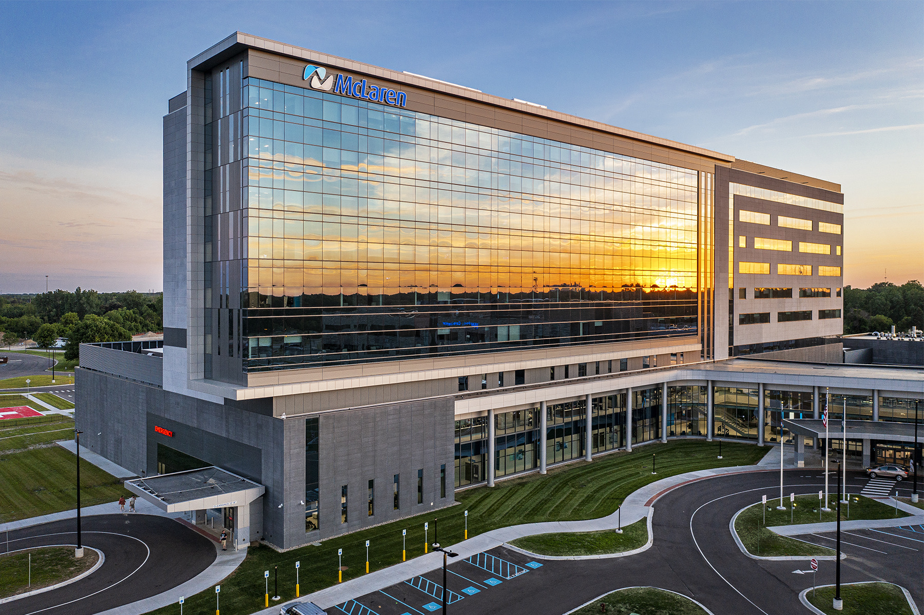 exterior of a nine-story hospital with a large glass façade reflecting the sunset