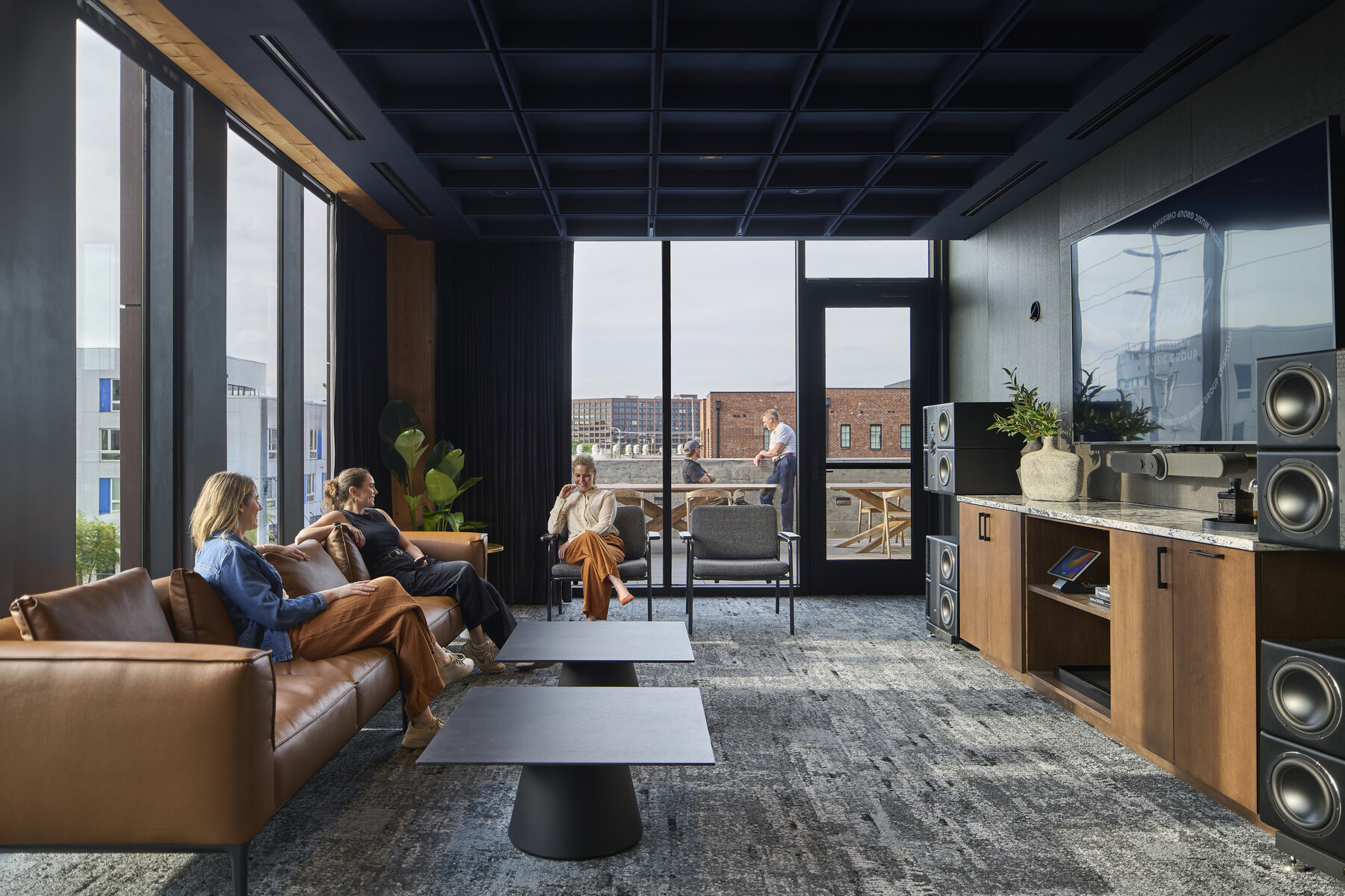 Three people sitting on a couch and two people on an outdoor terrace in an office