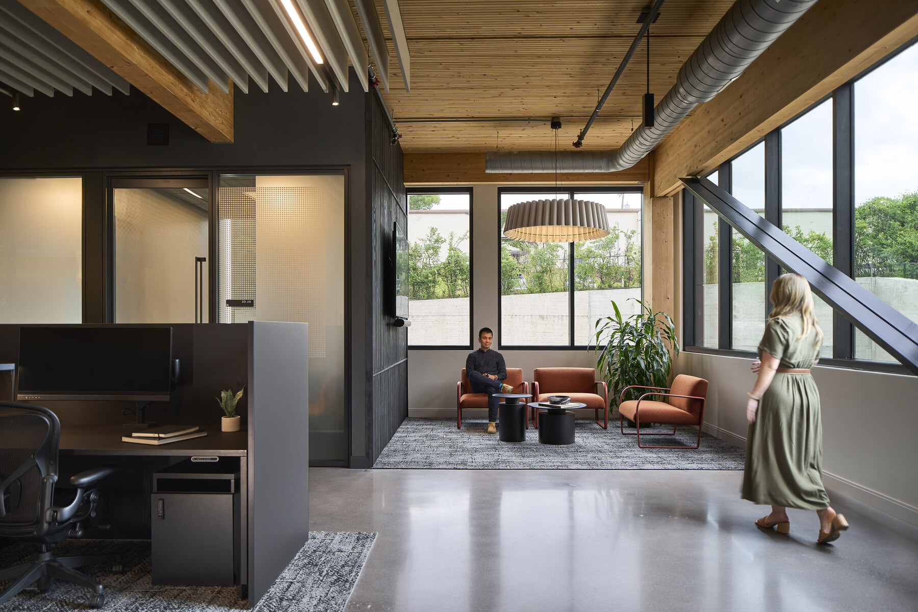 One person walking and one person sitting in a chair in an office