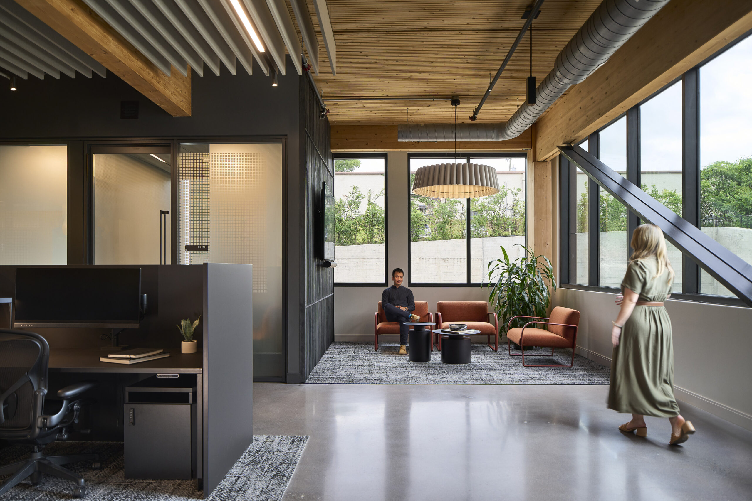 One person walking and one person sitting in a chair in an office
