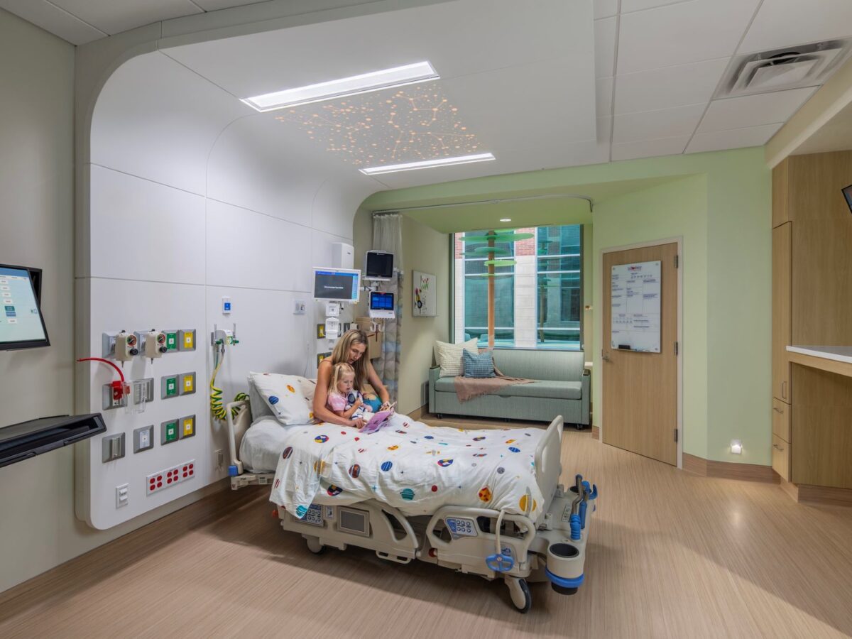 a family member and child sitting in a hospital bed in a patient room