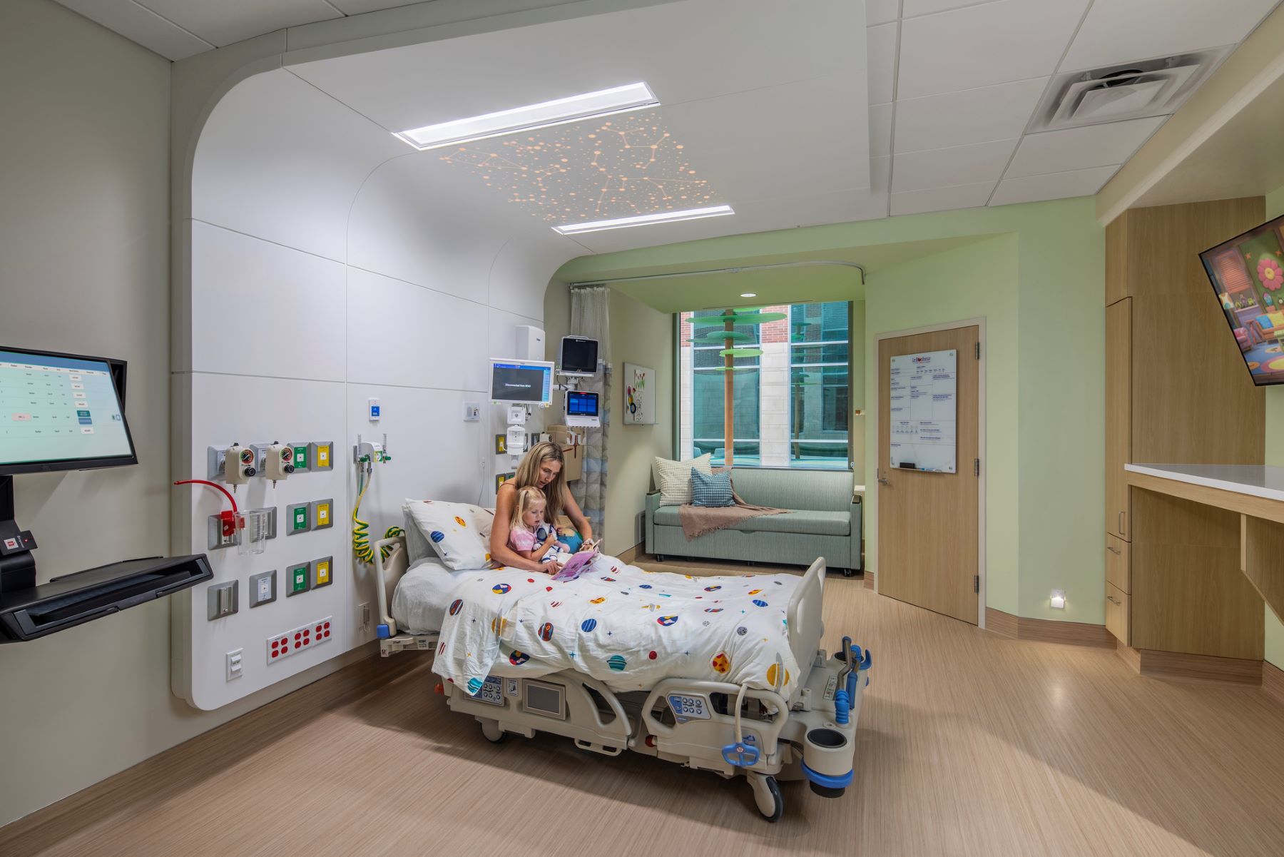 a family member and child sitting in a hospital bed in a patient room