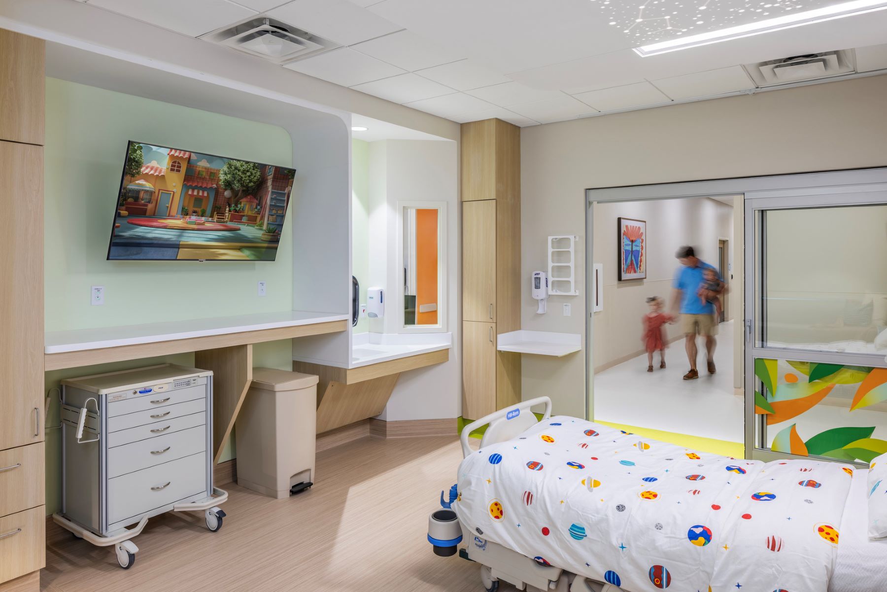 a family member and child walking through the doorway into a patient room