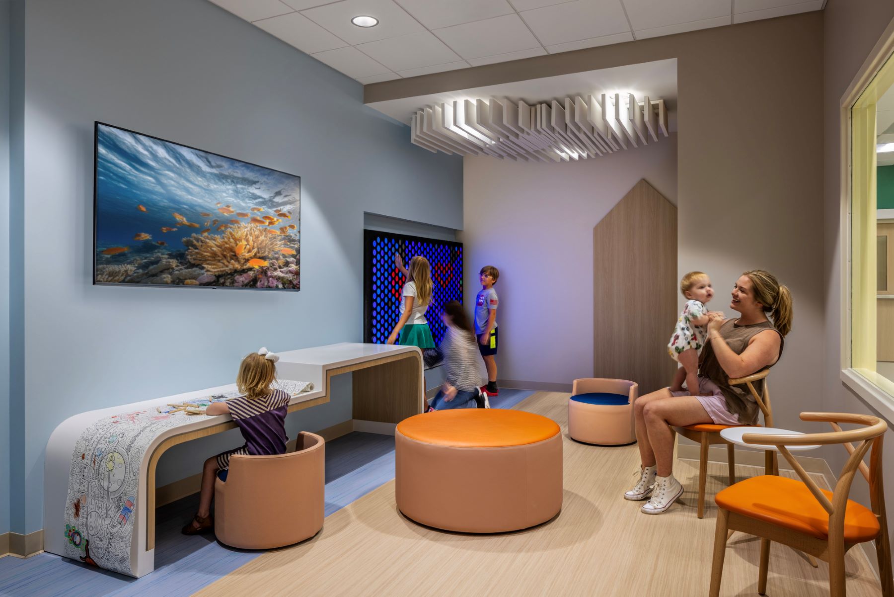 an adult and multiple children playing in a waiting area of a hospital