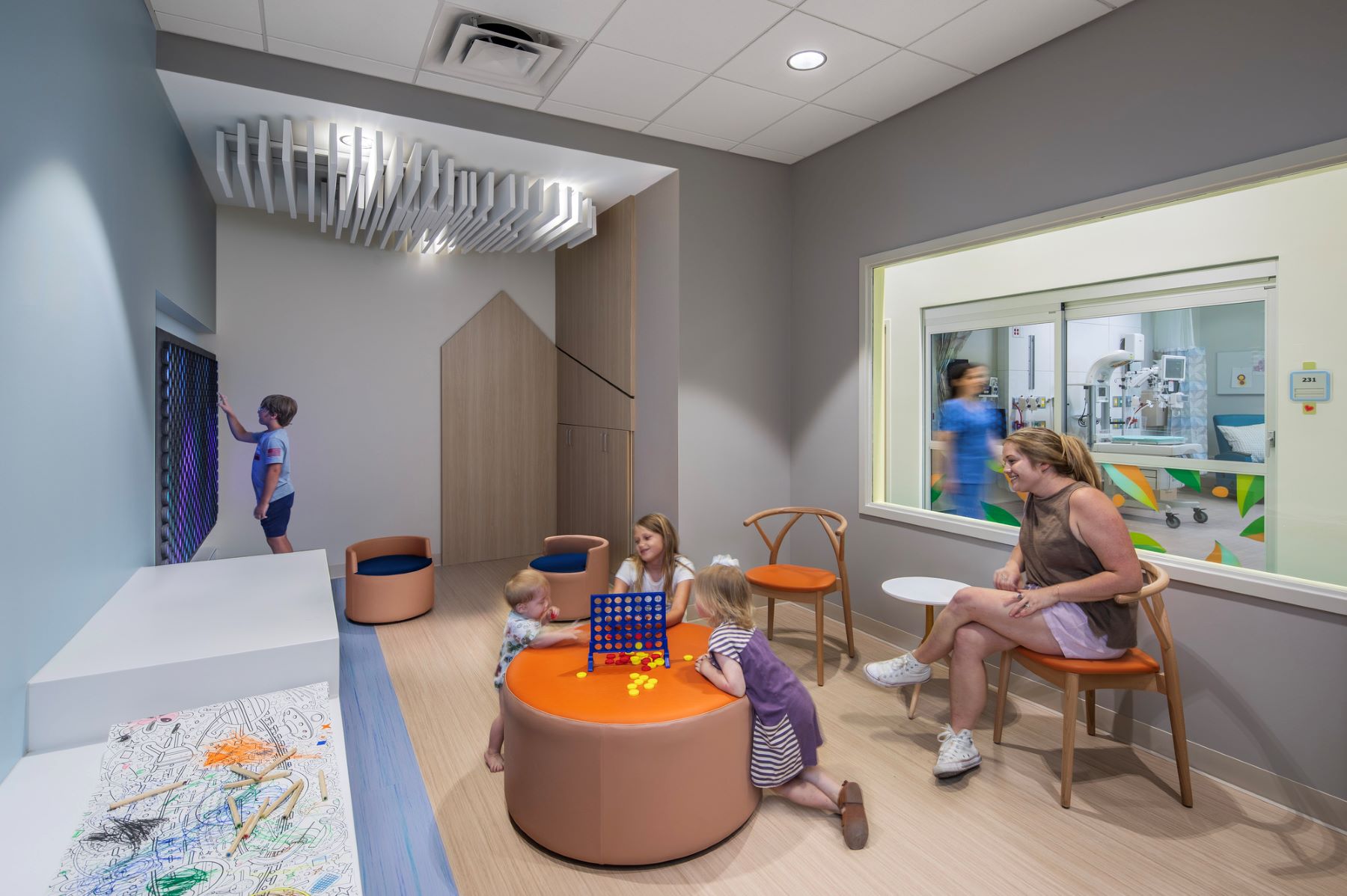 an adult and multiple children playing in a waiting area of a hospital