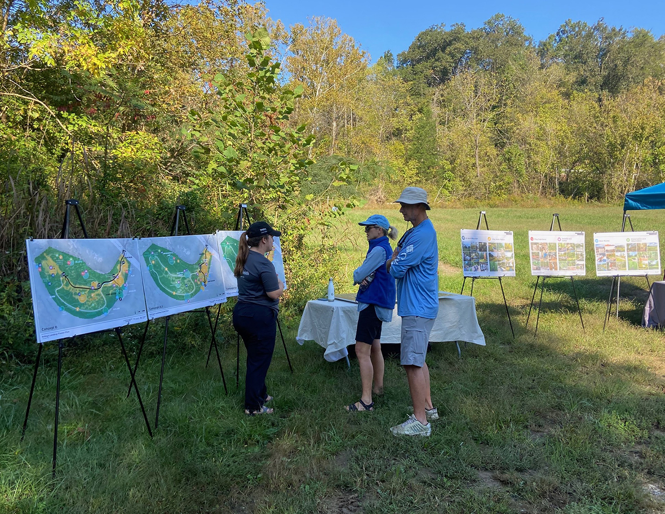 Three people standing outside and looking at board with images on them