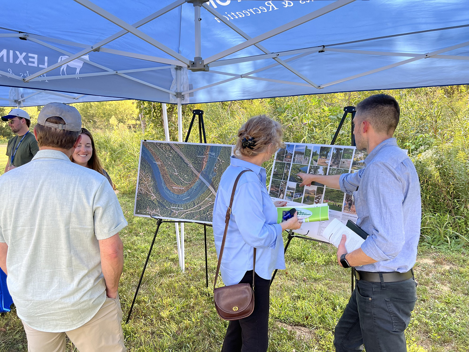 People standing under a tent and looking at pictures on a board