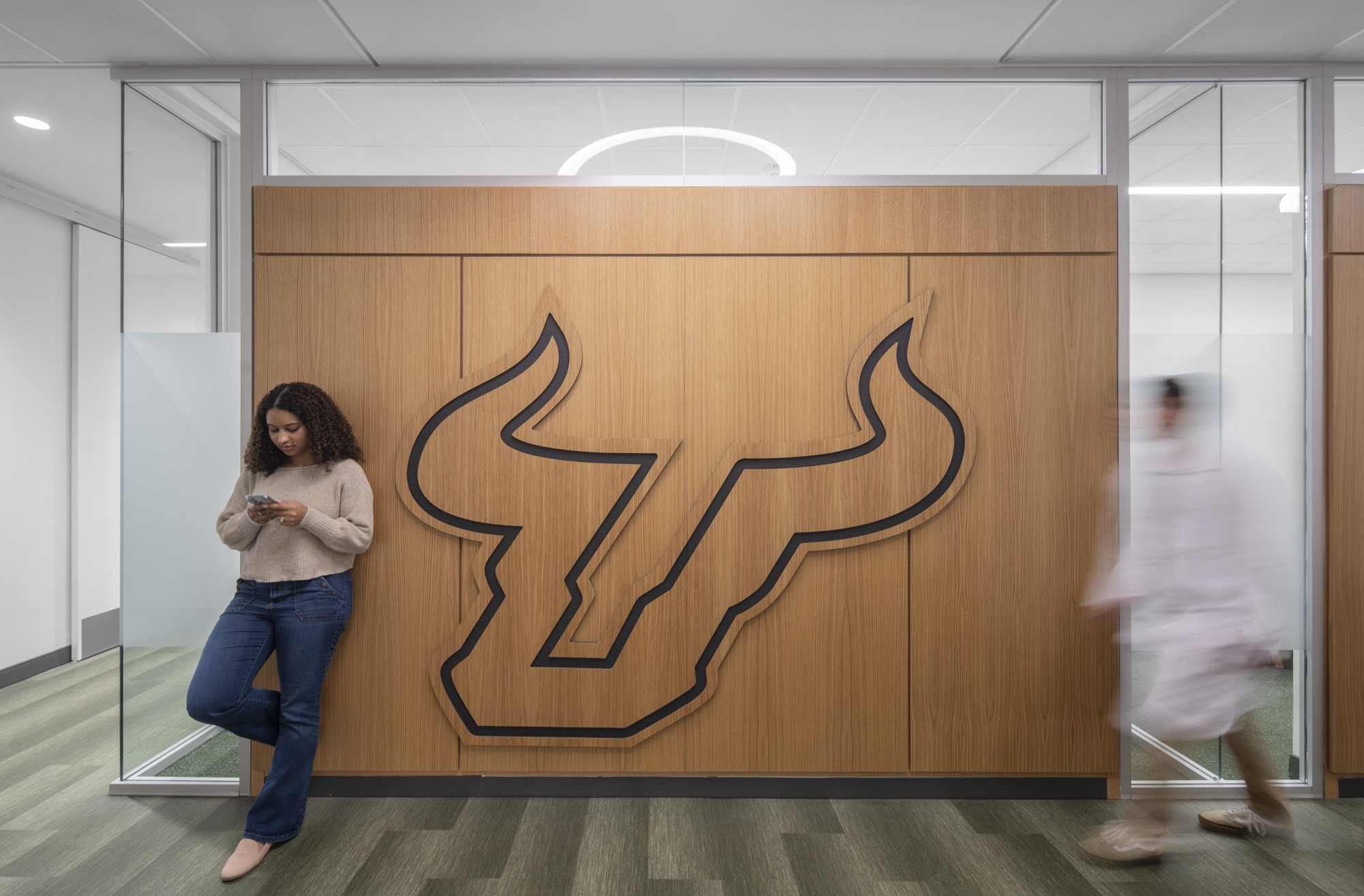 Student standing in USF College of Pharmacy with logo in background